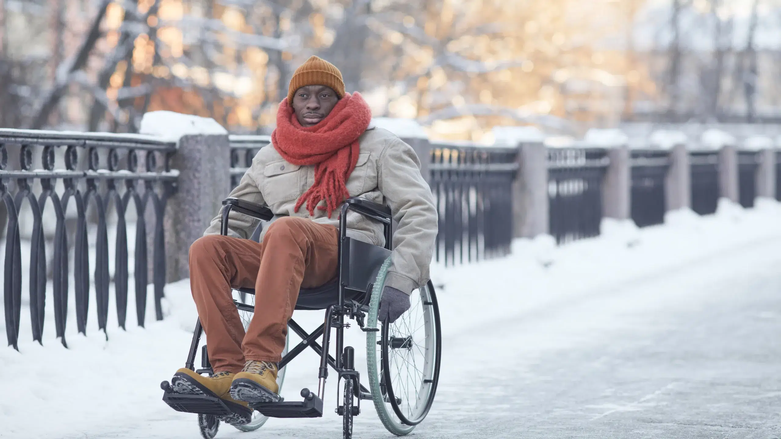 a man in a wheelchair on a snowy sidewalk