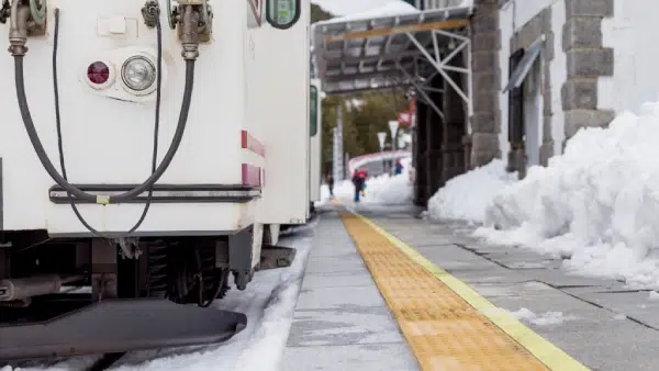 a train pulling up to a station during winter